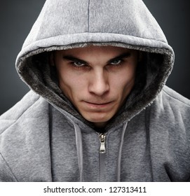 Close-up portrait of threatening gangster wearing a hood, representing the concept of danger