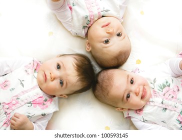 Close-up Portrait Of Three Babies Lying On Floor