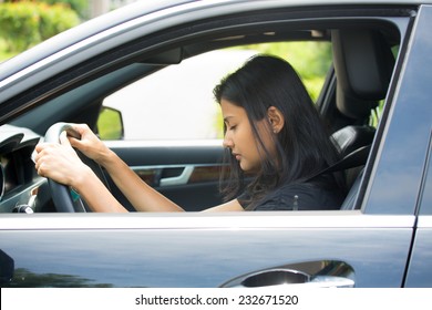 Closeup portrait tired young attractive woman with short attention span, driving her car after long hours trip, trying to stay awake at wheel, isolated outside background. Sleep deprivation