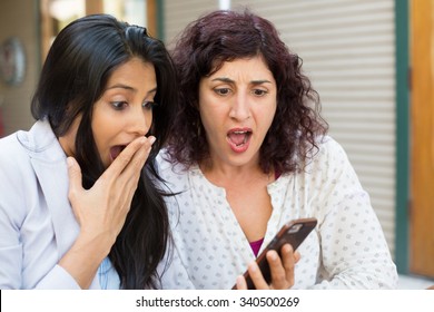 Closeup Portrait Two Surprised Girls Looking At Cell Phone Discussing Latest Gossip News, Shopping, Flabbergasted At What They See, Isolated Outdoors Background