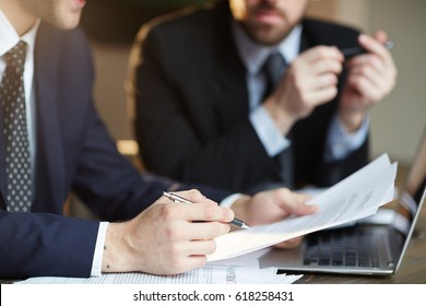 Closeup Portrait Of Two Unrecognizable  Business Partners Reviewing Paperwork And Signing Contract Papers At Table During Meeting