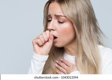 Closeup Portrait Of Unhealthy Young European Blonde Woman Coughing A Lot, Suffering With Cough, Has A Chest Pain/ Sick Desperate Female Has Flu/Cold, Sickness, Bronchitis Concept/Fit Of Coughing 