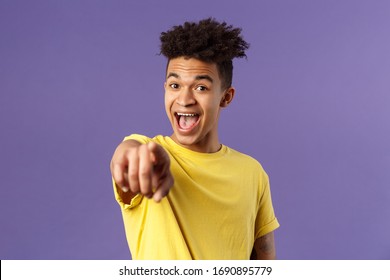 Close-up portrait of upbeat, amazed hispanic man with dreads, young student pointing finger at camera and laughing, recognize someone familiar, standing purple background - Shutterstock ID 1690895779