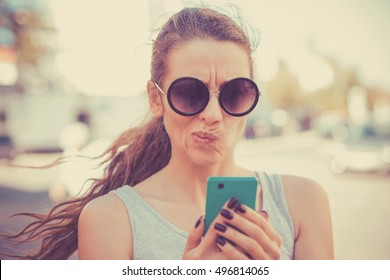 Closeup Portrait Upset Sad, Skeptical, Unhappy, Serious Woman Talking Texting On Phone Displeased With Conversation Isolated Outdoor Background. Negative Human Emotion Facial Expression. Bad News