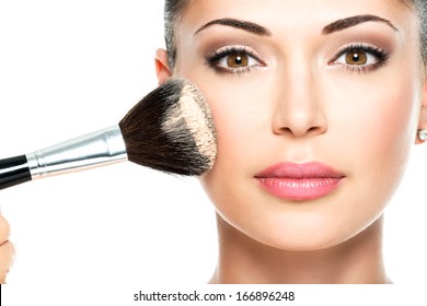 Closeup portrait of a woman  applying dry cosmetic tonal foundation  on the face using makeup brush. 