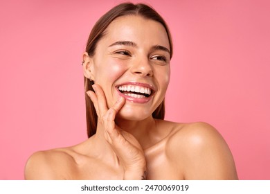 A closeup portrait of a woman with a bright smile, clear and glowing skin, hand on her face on a pink backdrop, showing her natural beauty and confidence, radiating positivity and happiness - Powered by Shutterstock