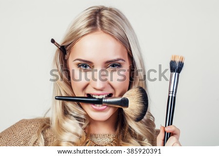 Closeup portrait of woman with makeup brush near face