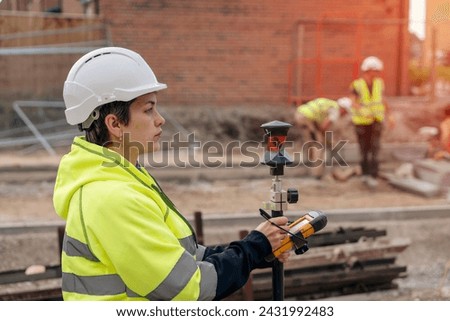 Close-up portrait of a woman site engineer surveyor working with theodolite total station EDM equipment on a building construction site outdoors