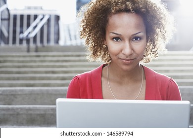 Closeup portrait of a young African American woman with laptop on steps outdoors - Powered by Shutterstock