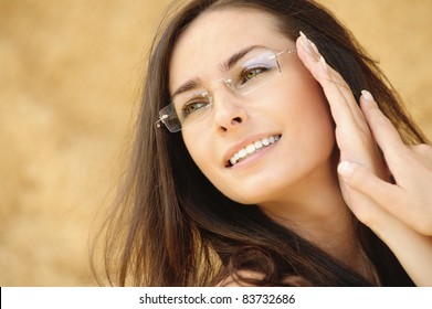 Close-up portrait of young alluring woman wearing eyeglasses against beige background.