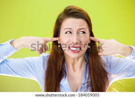 Closeup portrait, young annoyed, unhappy, stressed woman covering her ears, looking up, to say, stop making loud noise, giving me headache, isolated green background. Negative emotion, reaction.