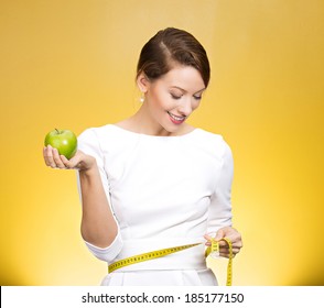 Closeup portrait young attractive, happy,  fit woman in white dress, holding green apple, measuring her waist, isolated yellow background. Healthy life style, nutrition. Positive emotion, expression - Powered by Shutterstock