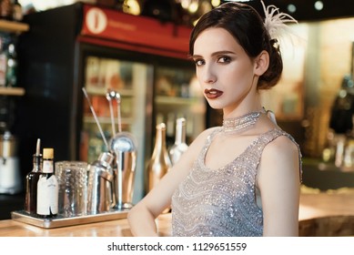 Close-up portrait of a young attractive woman in a 1920s style at the bar. Model with a beautiful make-up