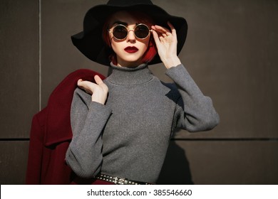 Closeup portrait of young beautiful fashionable woman with sunglasses. Lady posing on dark grey background. Model wearing stylish wide-brimmed hat. Girl looking at camera. Female fashion.Toned
