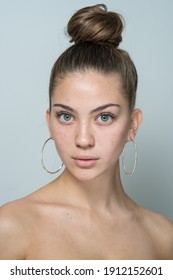 close-up portrait of a young beautiful girl on a gray background. girl without makeup with problematic skin. acne, acne, skin redness.