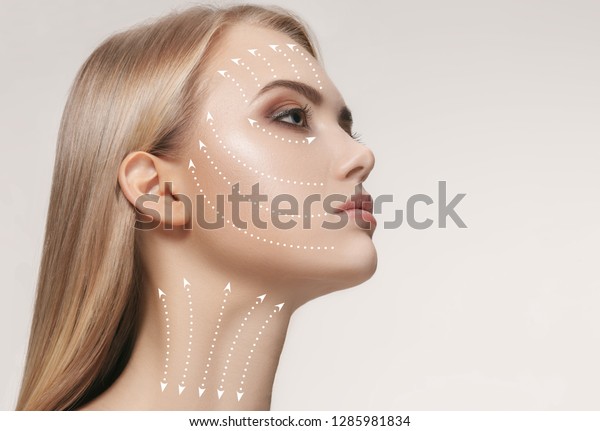 Close-up portrait of young, beautiful and healthy\
woman with arrows on her face. The spa, surgery, face lifting and\
skin care concept