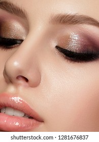 Closeup portrait of young beautiful woman with evening make up. Pink and gold multicolored smokey eyes. Luxury skincare and modern fashion makeup concept. Studio shot. Extreme closeup, partial face