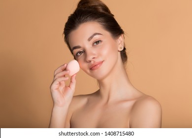 Closeup portrait of young beautiful woman is holding beauty blender for applying makeup foundation . Skin care and beauty concept.