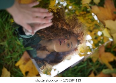 Close-up portrait of a young beautiful woman looking to her own reflection in the mirror. fingers touching the mirror. autumn season. - Powered by Shutterstock