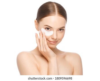 Close-up Portrait Of Young Beautiful Woman With Glowing Naked Skin, Wearing One Eyepatch To Eliminate Puffiness, Isolated On White Background