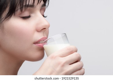 closeup Portrait of young beautiful woman with closed eyes drinking milk from a transparent glass 