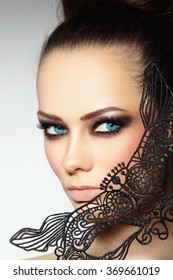 Close-up portrait of young beautiful woman with smoky eyes and lacy black mask