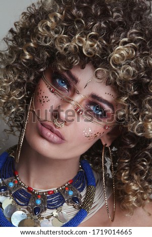 Close-up portrait of young beautiful woman with afro hair and fancy ethnic makeup