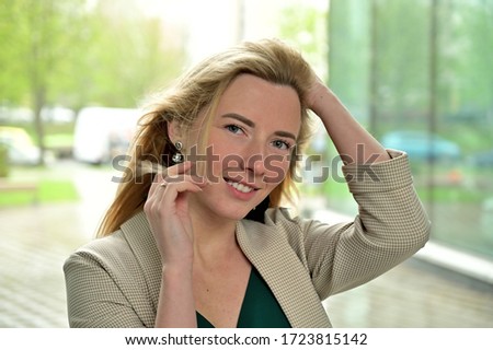 Close-up portrait of a young business woman blonde smiling on a background of a city outdoors. Model posing in a business suit.