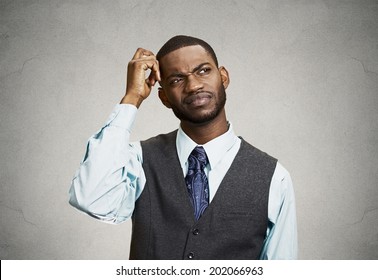 Closeup portrait young company business man thinking, daydreaming trying hard to remember something looking upward, isolated black background. Negative emotions, facial expressions, feelings, reaction
