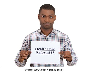 Closeup Portrait Of A Young Confused Skeptical Man Holding A Sign Health Care Reform, Hoping For Universal Health Care Coverage, Isolated On A White Background. Politics, Government , Legislation