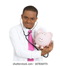 Closeup Portrait, Young Curious Male Man Health Care Professional, Doctor, Nurse Listening Piggy Bank With Stethoscope. Medical Insurance, Medicare Reimbursement Concept. Health Law Coverage. Budget