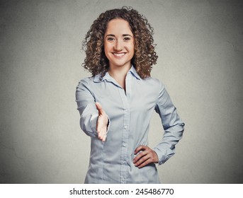 Closeup portrait, young, curly, brown hair, smiling woman, student, customer service agent giving you handshake isolated grey wall background. Positive human emotions, feelings, face expressions