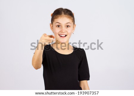 Closeup portrait young cute excited, happy smiling, laughing, little girl pointing finger towards you, camera gesture isolated grey background. Positive human emotion, attitude, reaction, perception