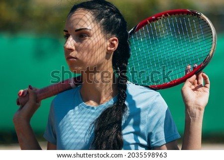 Close-up portrait of young female tennis player holding racket. Active sport lifestyle. Concept of sport, physical strength, health, sport spirit.