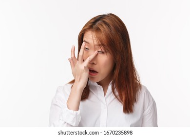 Close-up Portrait Of Young Funny Asian Woman Scratching Eye, Rolling It Up As Something Stuck Trying Reach With Finger, Standing White Background Having Spring Seasonal Allergy