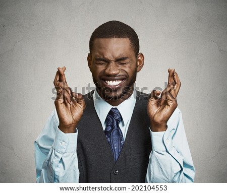 Closeup portrait young funny guy, business man crossing fingers, wishing, hoping for best, miracle isolated black, grey background. Positive human emotions, facial expressions, feelings, attitude