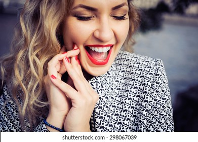 close-up portrait of a young girl hipster beautiful blonde in sunglasses with red lips laughing and posing against the backdrop of the city