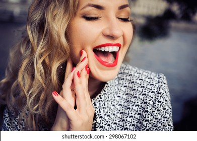 close-up portrait of a young girl hipster beautiful blonde in sunglasses with red lips laughing and posing against the backdrop of the city - Powered by Shutterstock
