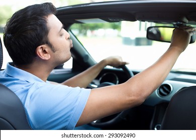 Closeup Portrait, Young Handsome Egotistical Man In Blue Polo Shirt Looking At Mirror Showing Kisses And Duck Face, Admiring His Appearance Inside Interior Black Sports Car