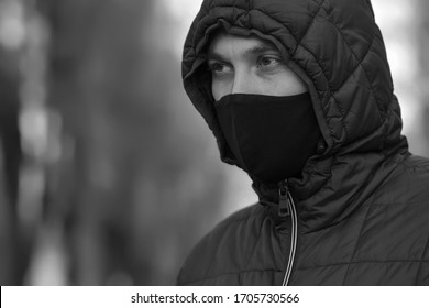 Close-up portrait of a young handsome European man in a black protective mask to protect against infection by influenza virus or coronavirus.Black and white photography