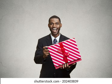 Closeup Portrait Young Happy Excited Man Opening Red Gift Box, Pleased, Grateful With What He Received, Isolated Black, Grey Background. Positive Human Emotions, Facial Expressions, Feelings, Attitude