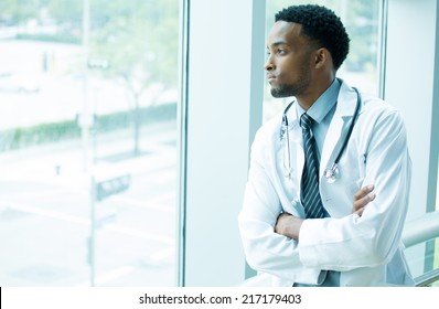 Closeup portrait, young healthcare professional, folding arms crossed, daydreaming looking outside, isolated indoors hospital clinic background - Powered by Shutterstock