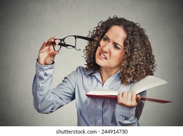 Closeup portrait young lady, woman can't see read book has vision problems wrong glasses prescribed upset isolated grey wall background. Human emotion facial expression, feeling health issue reaction - Powered by Shutterstock