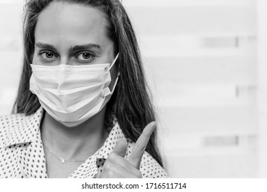 Retrato de una joven marrón claro con una máscara médica sobre un fondo claro. El dedo señala el lugar para la inscripción. Cuarentena.Quédate en casa. Concepto de pandemia del coronovirus covid-19.