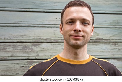 Closeup portrait of young man slightly smiling over old wooden wall - Shutterstock ID 103908875