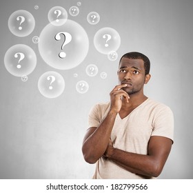 Closeup portrait young man thinking daydreaming deeply about something finger on lips looking away up isolated grey background. Negative emotion facial expression feeling reaction situation perception