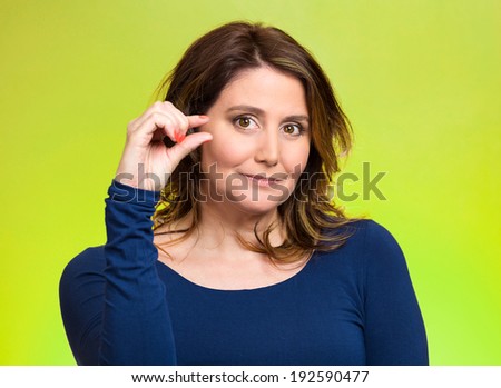 Closeup portrait, young middle aged woman, showing small amount gesture with hands, isolated green background. Negative human emotion facial expression feelings, body language, sign, symbol, reaction