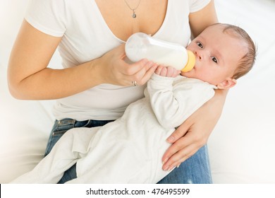 Closeup Portrait Of Young Mother Holding Her Baby And Feeding With Milk From Bottle