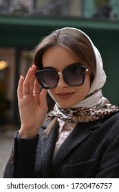 Closeup portrait of young pretty fashionable woman with sunglasses and scarf.Advertising clothing store and accessories.Stock foto - Shutterstock ID 1720476757