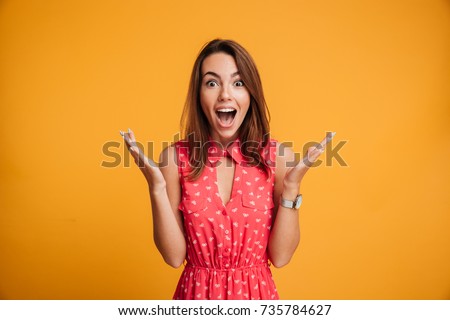 Close-up portrait of young pretty surprised woman with opened mouth standing with open palms, isolated on yellow background